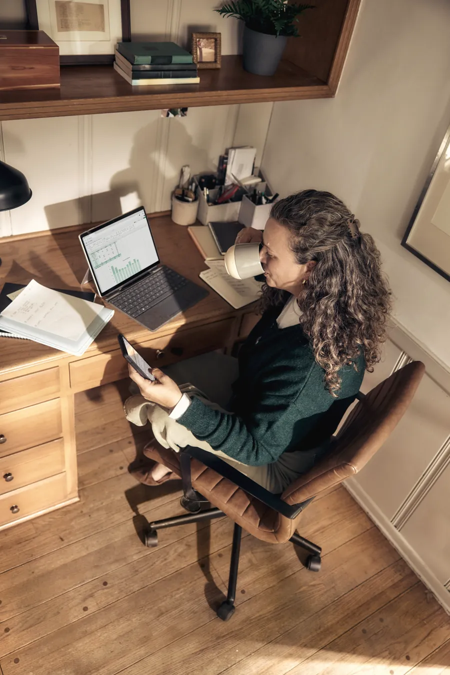 A marketer at a wooden desk with a laptop and her phone