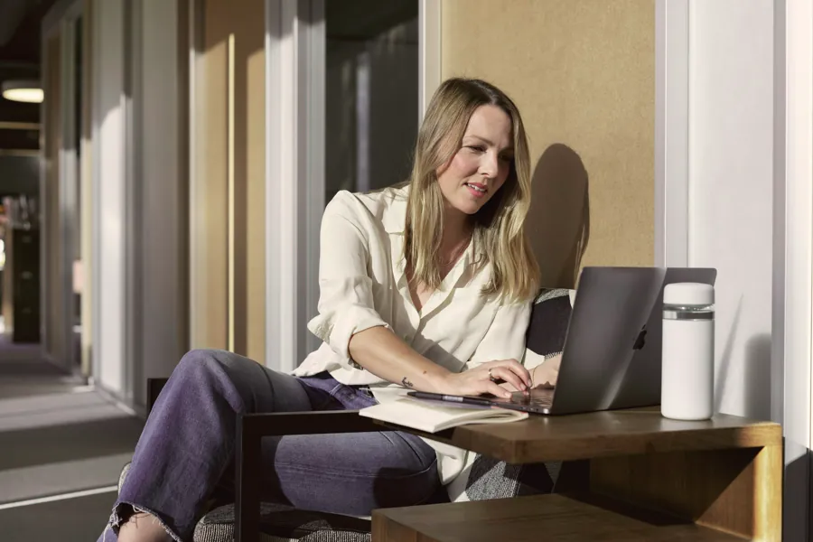 A support specialist smiling at her laptop at a small desk
