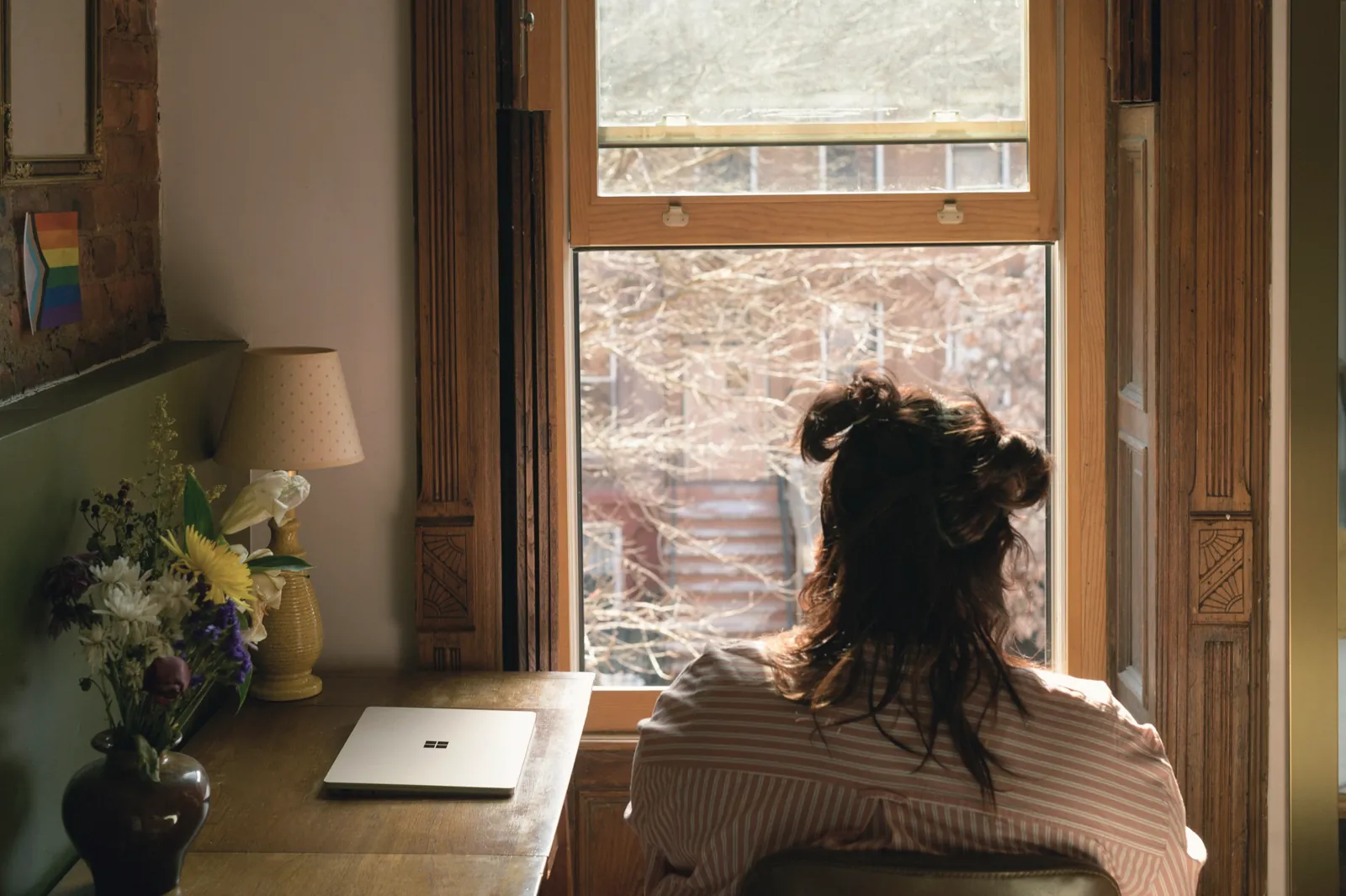 A woman at her desk by a tall window, looking out