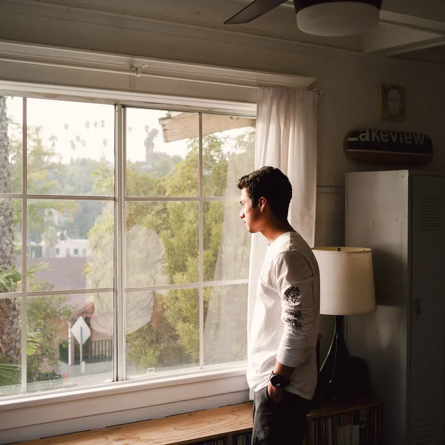 A man by a sunlit window, thinking